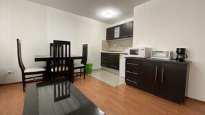 A compact kitchen with a dining table and chairs, a microwave, and a coffee maker. - Grupo Kings Suites Platon 436 (Mexico City)