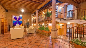 A spacious lobby with a tiled floor, a large abstract painting, and a staircase leading to an upper level. - Hotel Refugio del Angel (Patzcuaro)