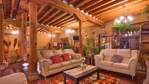 A spacious lobby with two sofas, a coffee table, and a colorful rug. - Hotel Refugio del Angel (Patzcuaro)