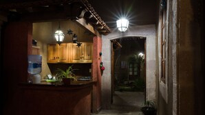 A narrow hallway with a kitchen area on the left, featuring wooden cabinets and a water dispenser. - Hotel Del Callejon (Morelia)