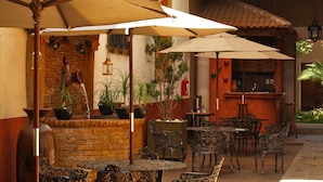 An outdoor patio with tables and chairs, umbrellas, and potted plants. - Hotel Del Callejon (Morelia)