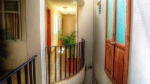 A narrow hallway with a curved balcony, potted plants, and wooden doors. - Hotel & Posada Refugio Independencia (Morelia)