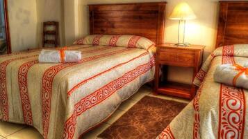 Habitación de hotel con dos camas, cabecero de madera, mesita de noche con lámpara y alfombra marrón.
