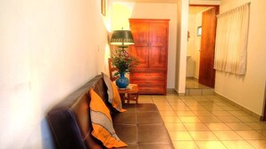 A living room with a brown sofa, a small table, a lamp, and a wooden cabinet. - Hotel & Posada Refugio Independencia (Morelia)