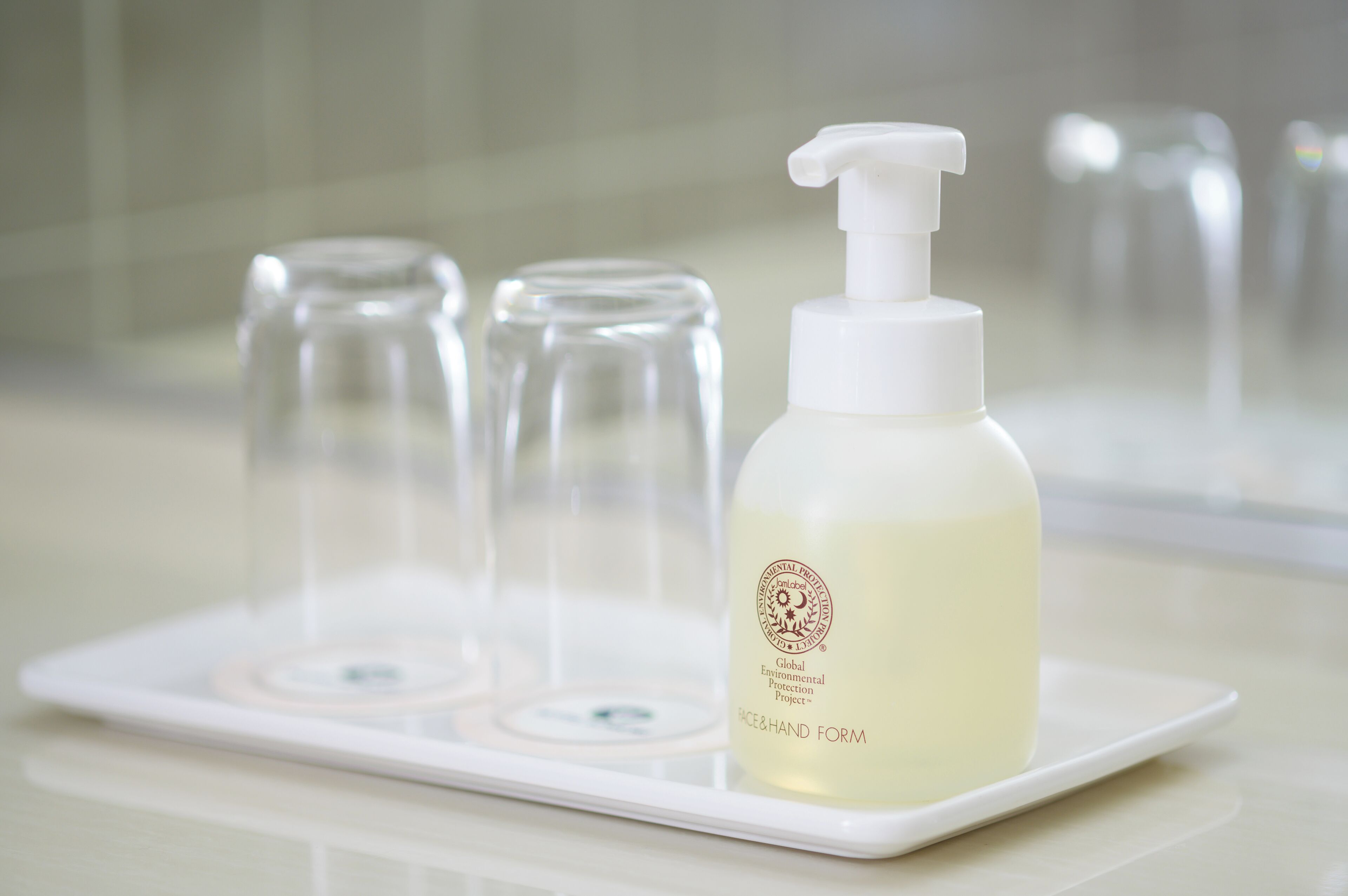 A bottle of liquid soap with a pump dispenser on a white tray.