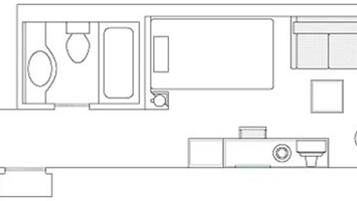 A floor plan with a bathroom, kitchenette, and a seating area.