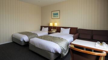 Quarto de hotel com duas camas, uma mesinha com bandeja e um sofá.