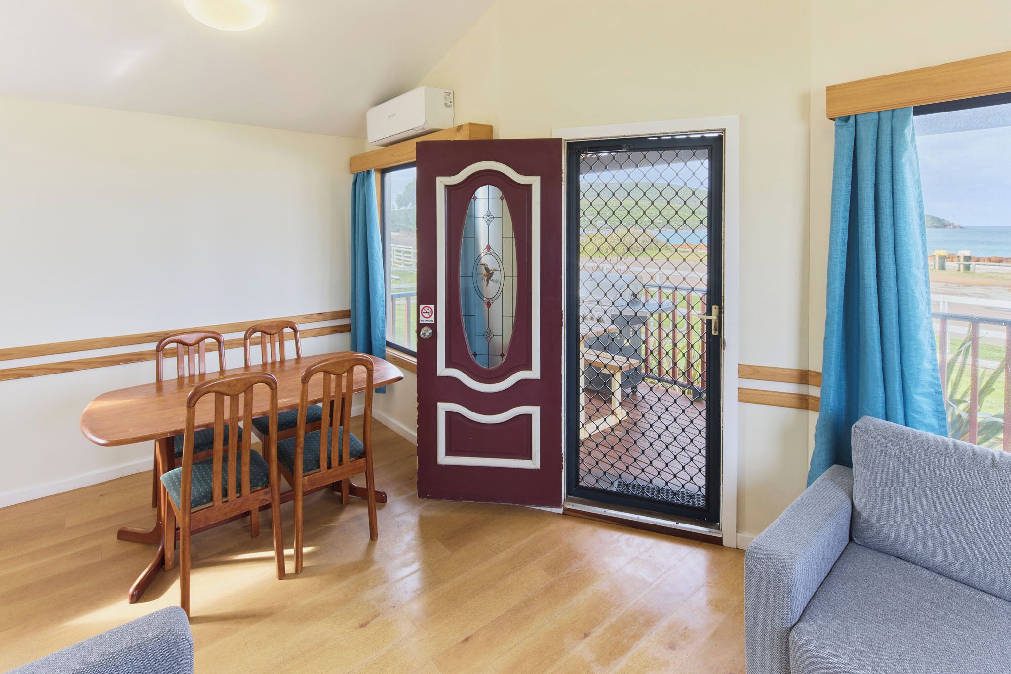 Une pièce comprenant une table à manger, des chaises, un canapé, une porte-fenêtre coulissante donnant sur une vue agréable et un petit balcon.