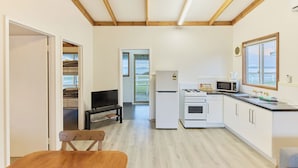A compact kitchen with white cabinets, a microwave, a stove, and a window overlooking a scenic view.