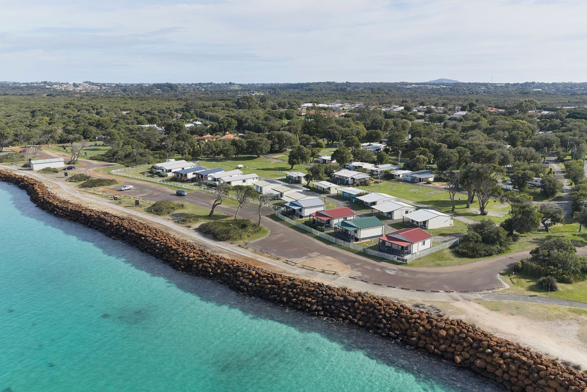 A coastal area with a row of houses along a rocky shoreline.