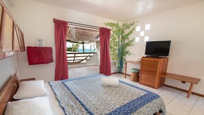 Une chambre à coucher avec un lit, une télévision, un banc et une vue sur l’extérieur.