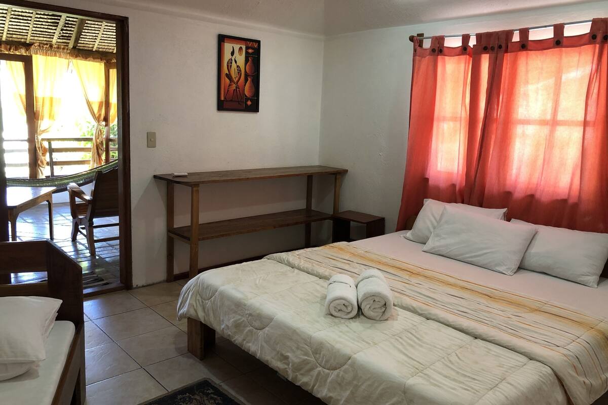 Un dormitorio con cama, almohadas, un escritorio y una silla.