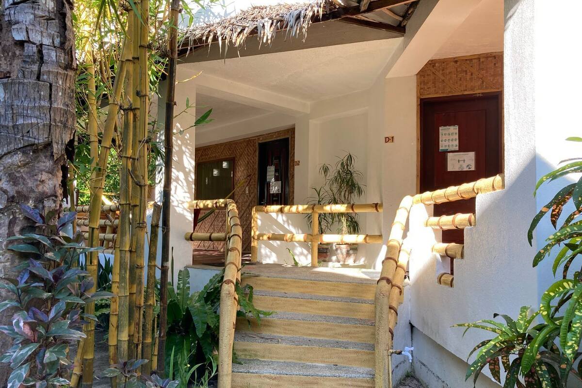 Una escalera con barandillas de bambú que lleva a la entrada de un edificio.