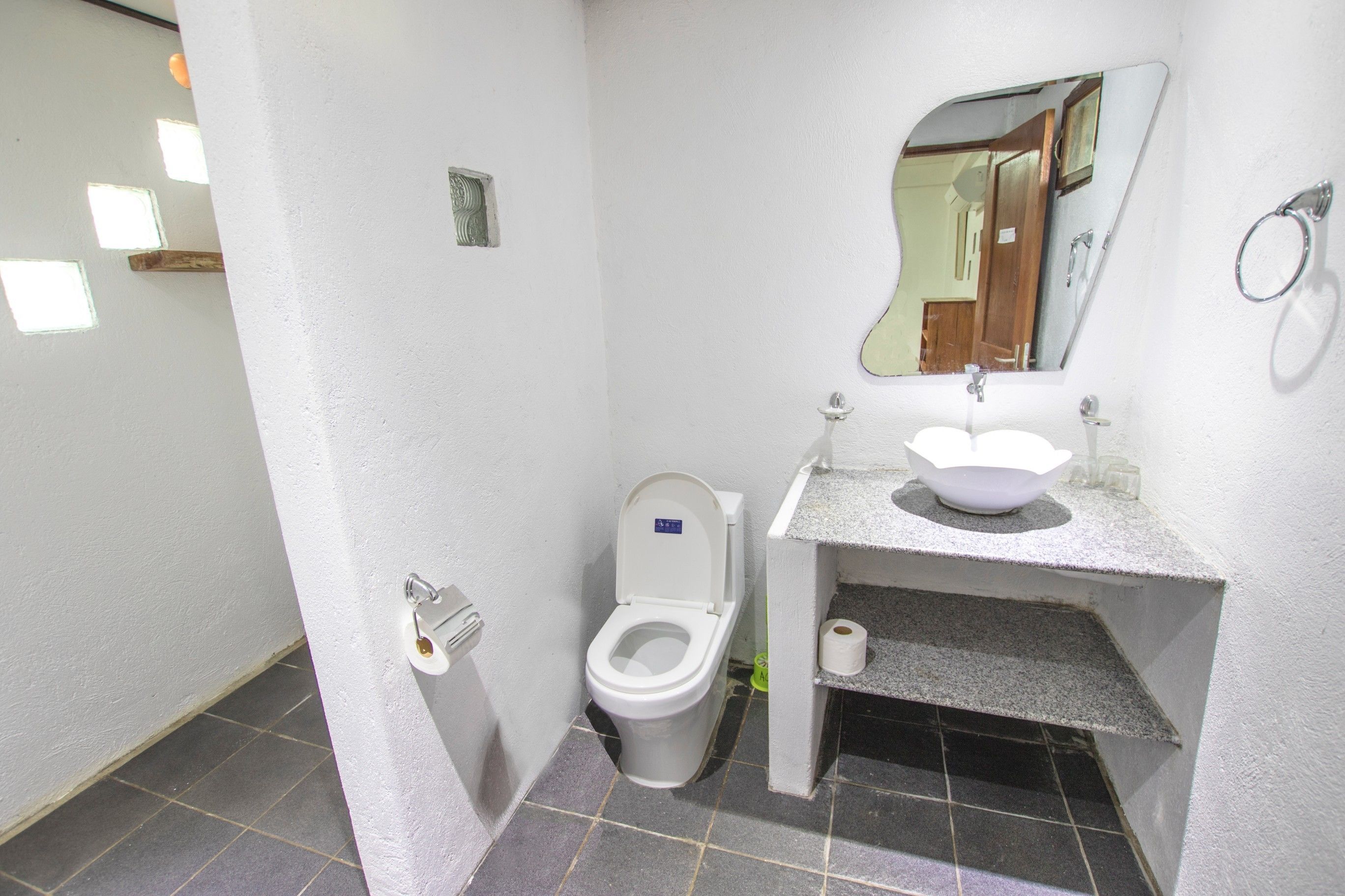 Un baño pequeño con inodoro, lavamanos y espejo.