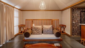 Une chambre moderne avec un lit en bois, un luminaire suspendu et un mur en pierre.