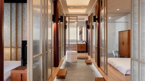 Une chambre d’hôtel moderne avec un coin salon central, un meuble en bois et une grande fenêtre.