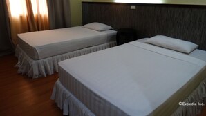 A hotel room with two single beds, a small round table, and a wooden headboard. - Panda Tea Garden Suites (Tagbilaran)