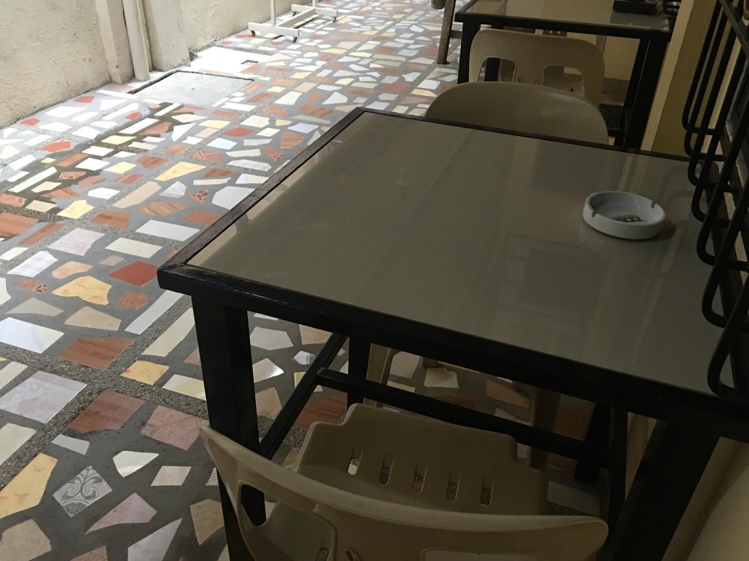 A tiled patio area with a glass table and chairs.