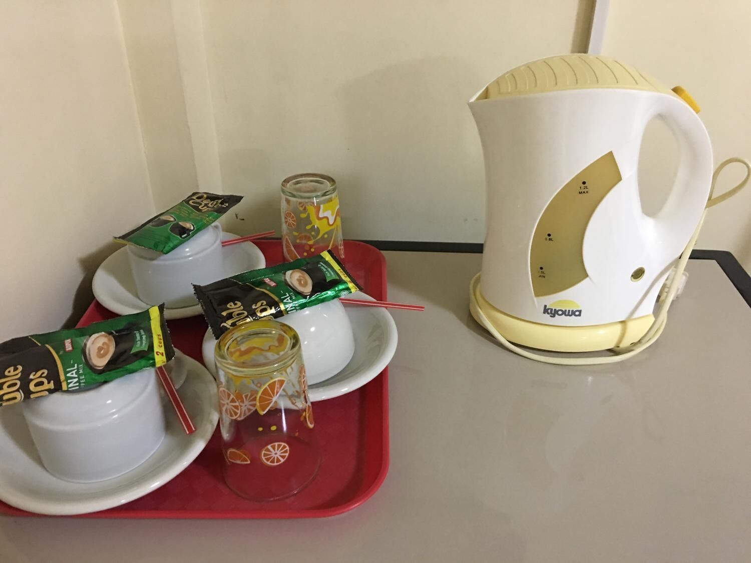 Un plateau avec une cafetière, des tasses et des sachets de thé.