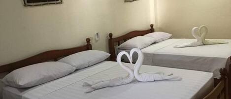 Two single beds with white linens and heart-shaped towels on the bed.