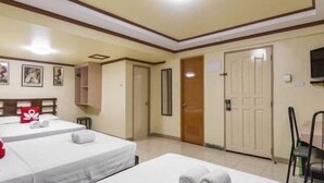 Una camera d'albergo con due letti, un armadio, una televisione e una porta.