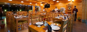 Restaurante com interior de madeira, várias mesas e cadeiras.