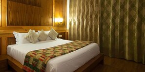 Uma cama bem arrumada com colcha, travesseiros e cabeceira de madeira.