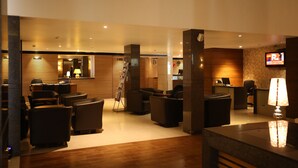A hotel lobby with a reception desk, seating area, and a television screen. - Hotel Moti Mahal (Mangaluru)