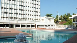 A swimming pool with a fountain, surrounded by a building with multiple floors and balconies. - Hotel Moti Mahal (Mangaluru)