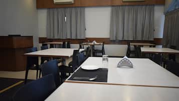 A dining area with tables and chairs, air conditioning units, and curtains.