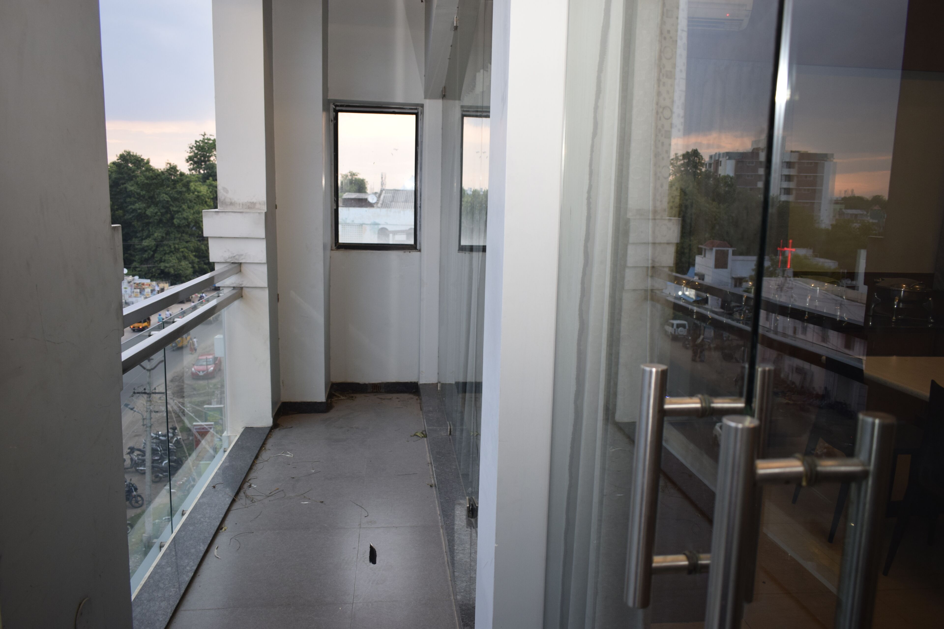 A narrow corridor with a glass railing on one side, a window, and a metal gate on the other.