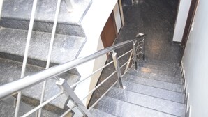 A staircase with metal handrails, stone steps, and a white wall. - Hotel The Nook (Madurai)