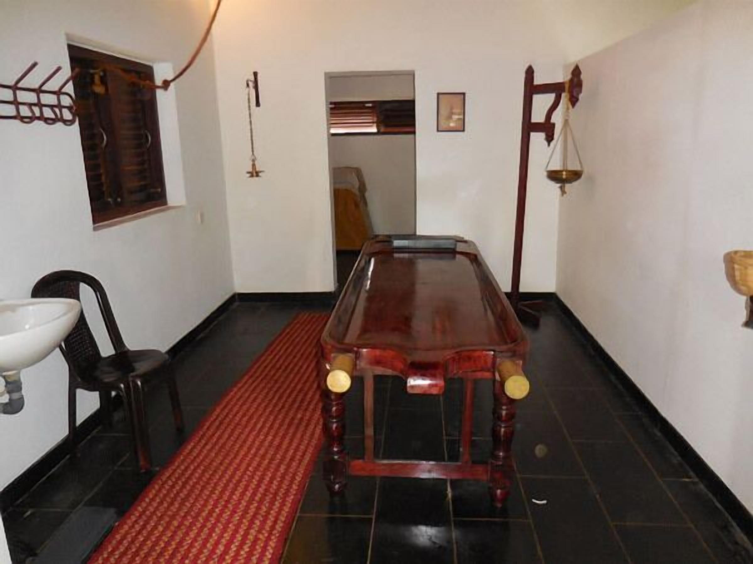 A narrow hallway with a wooden bench, a red patterned rug, a sink, and a scale on the wall.