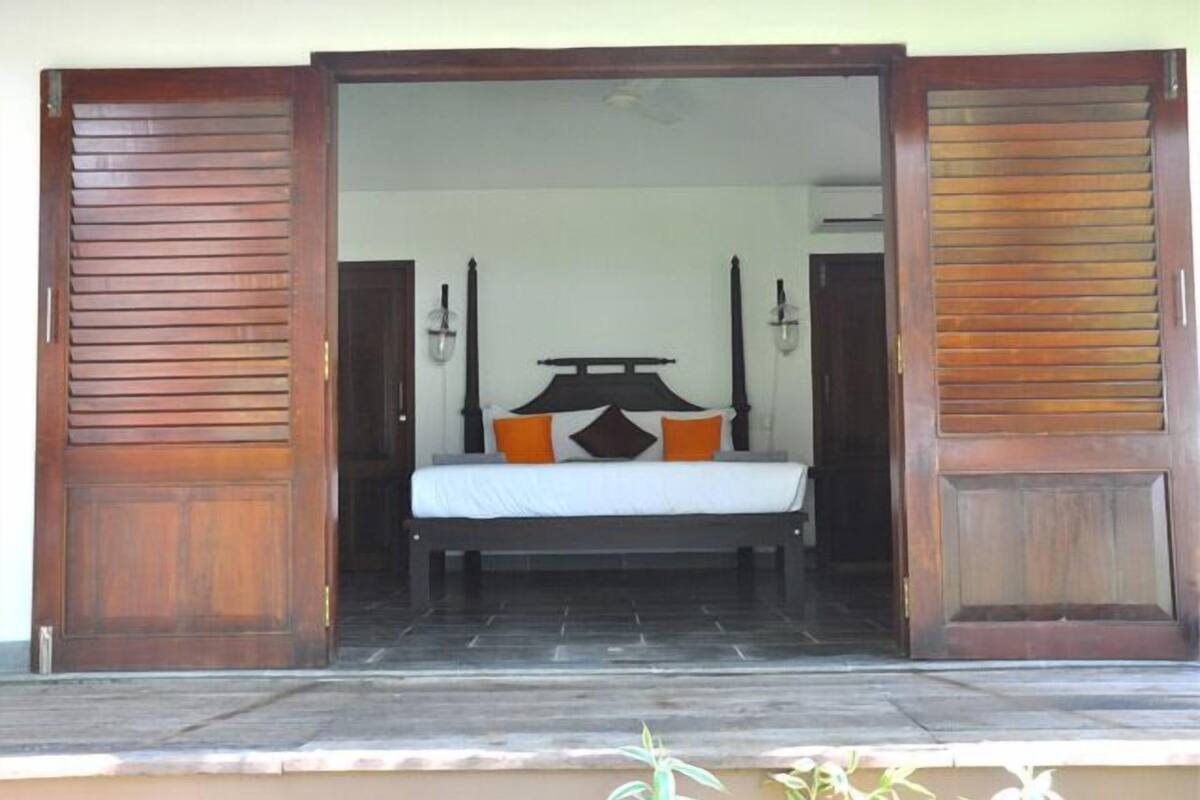 Um quarto com cama, duas mesas de cabeceira e porta de madeira.