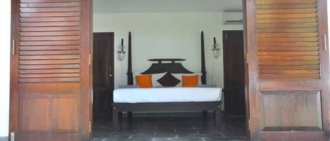 Un dormitorio con una cama, dos mesitas de noche y una puerta de madera.