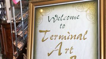 A framed welcome sign for Terminal Art Inn with a decorative border and floral design.