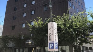 A multi-story building with a parking sign indicating a parking area. - Terminal Art Inn (Niigata)