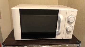 A white microwave oven on a dark wooden table.