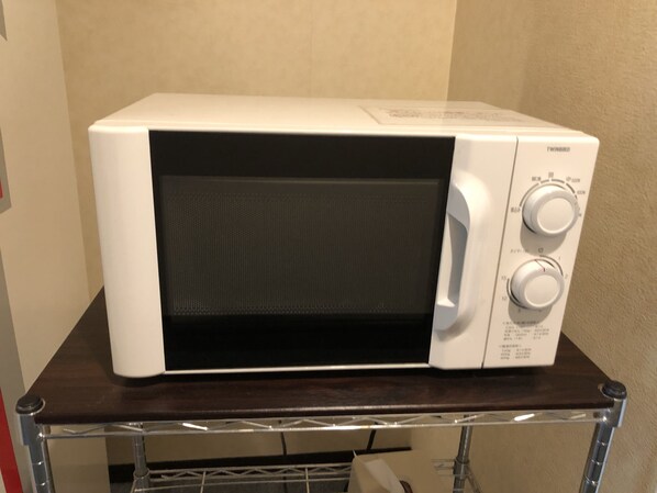 Un four à micro-ondes blanc posé sur une table en bois foncé.