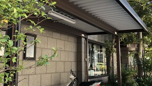 A modern building with a covered entrance, a parked scooter, and a potted plant. - Terminal Art Inn (Niigata)