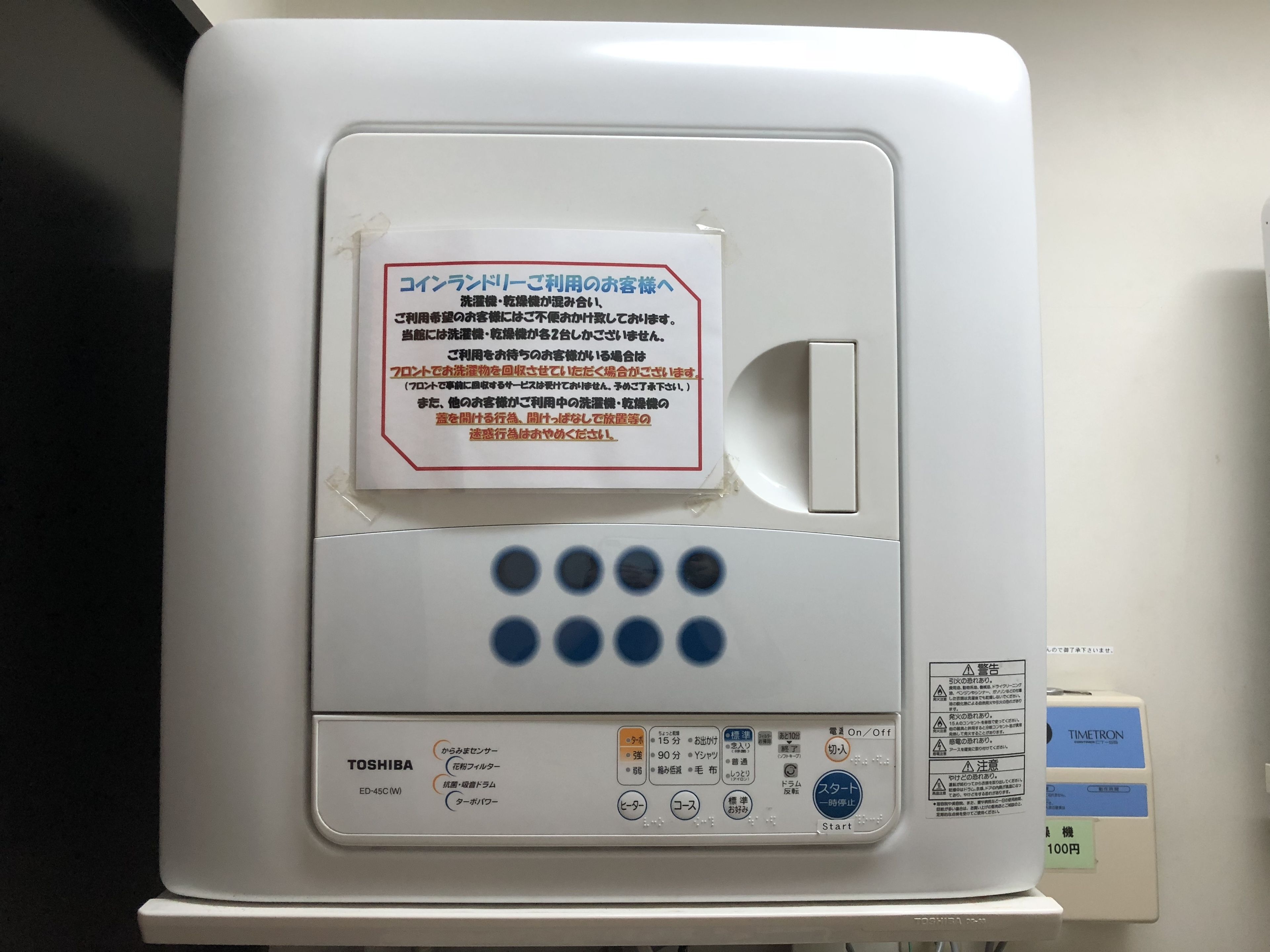 Un dispositiu electrònic blanc amb text i símbols japonesos, incloent un logotip de Toshiba i un preu de 100 iens.