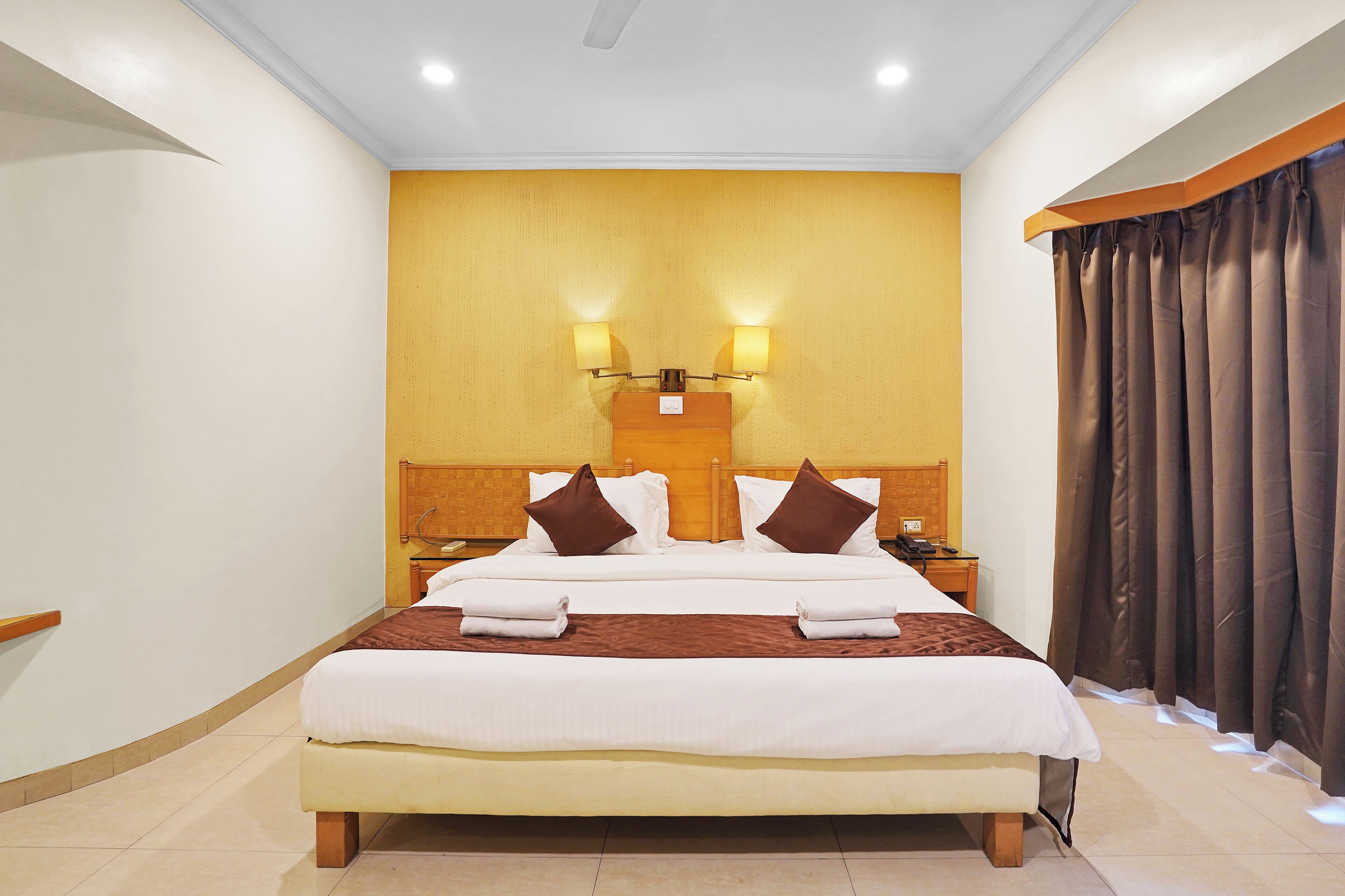 A double bed with a wooden headboard, two bedside tables, and a nightstand with a lamp.