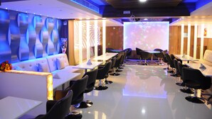 A modern conference room with a long table, black chairs, and a white sofa.