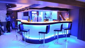 A modern bar area with a curved counter, bar stools, and a bartender.