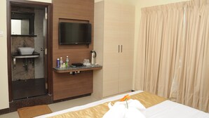 A hotel room with a bed, a bathroom with a sink, a mirror, a TV, and a wardrobe.
