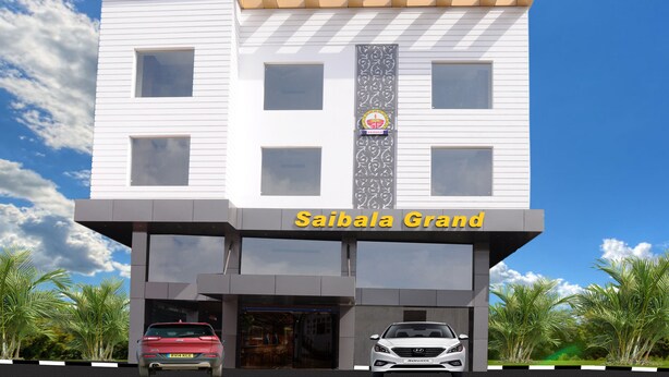 A modern building with the sign "Saibala Grand" and two cars parked in front.