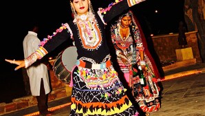 Eine Person in traditioneller Tracht, die mit einem verzierten Kopfschmuck tanzt.