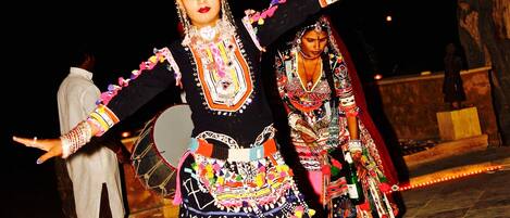 A person in traditional attire performing a dance with a decorated headpiece.