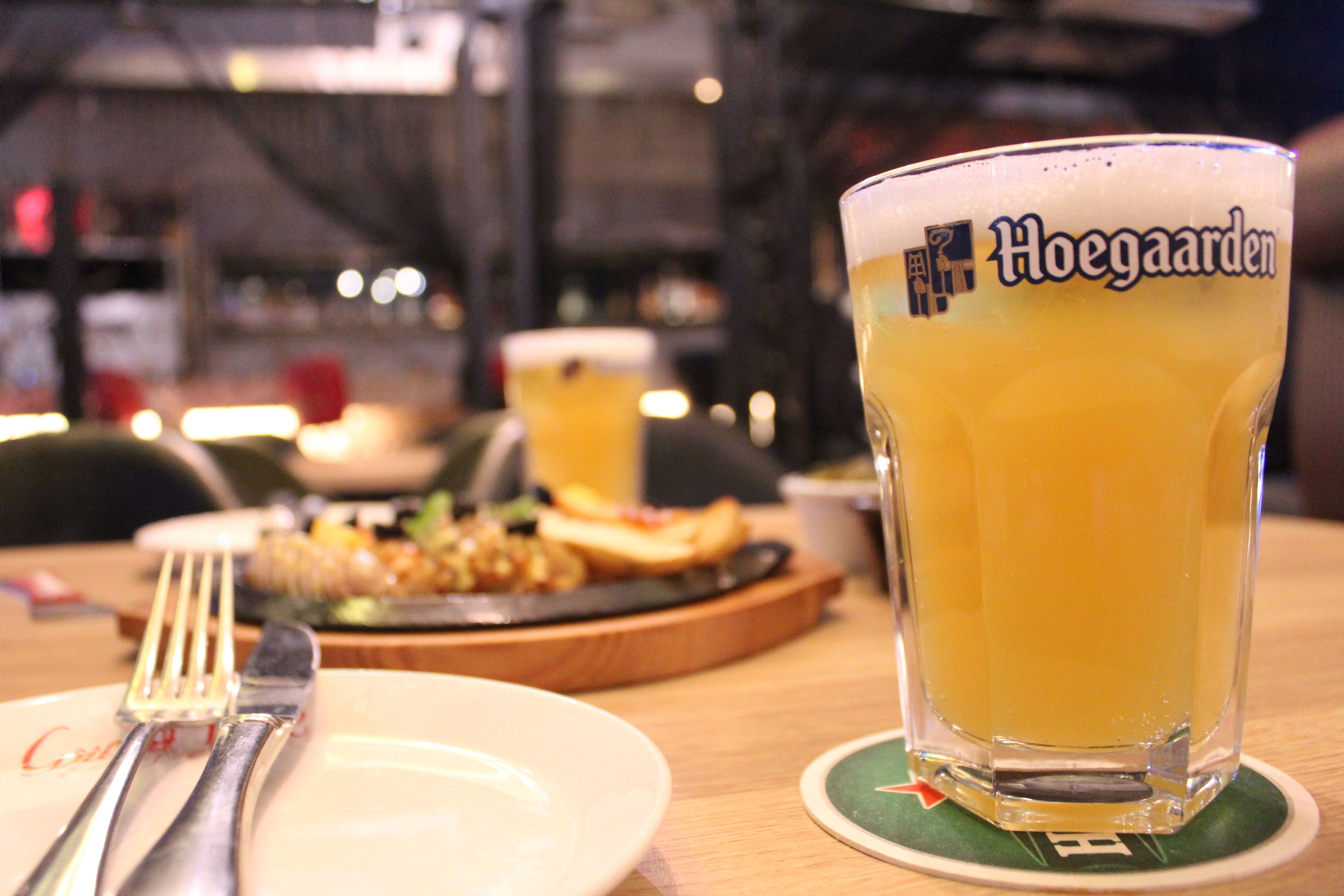 A glass of beer with a coaster on a table.