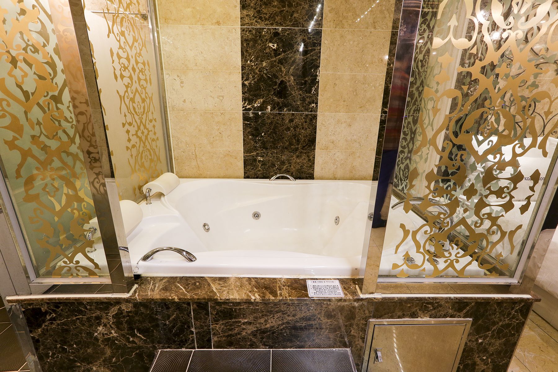 Ein Badezimmer mit einer großen Badewanne, Marmorböden und dekorativen Glasschirmen.